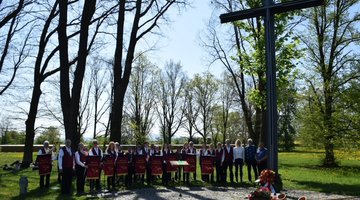 Gruppenfoto einer Musikkapelle am Hochkreuz einer Kriegsgräberstätte