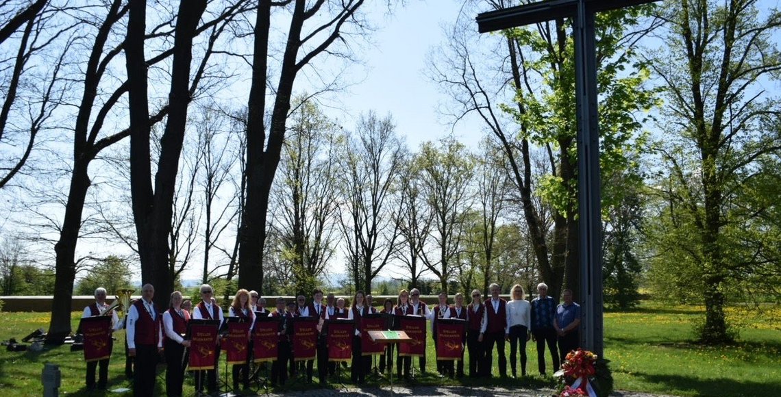 Gruppenfoto einer Musikkapelle am Hochkreuz einer Kriegsgräberstätte