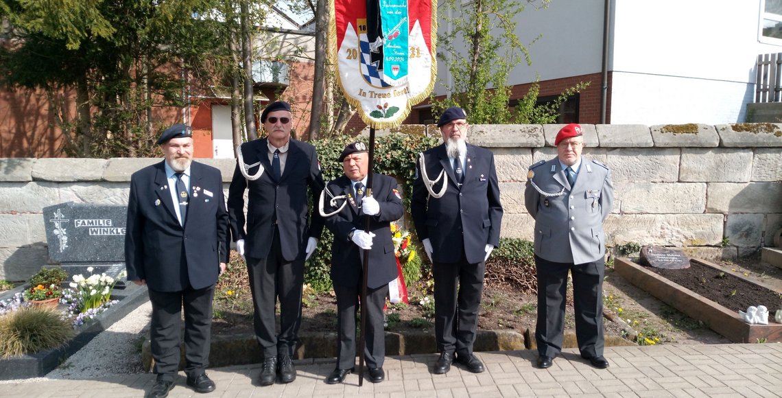 Personen in Vereinskleidung und Uniform vor einem Grab: Die Abordnung der SRK Zirndorf auf dem Friedhof Cadolzburg