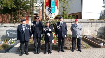 Personen in Vereinskleidung und Uniform vor einem Grab: Die Abordnung der SRK Zirndorf auf dem Friedhof Cadolzburg